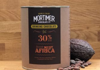 2 kg tin of 30% Drinking Chocolate sitting next to a cocoa pod and a sprinkling of cocoa beans