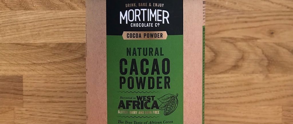 a lifestyle image of natural cacao powder with cocoa beans beside the product