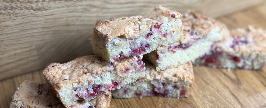 A white chocolate blondie with raspberry pieces in