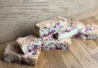 A white chocolate blondie with raspberry pieces in